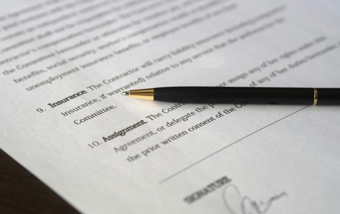 typed text of a contract agreement in black ink, printed on white paper, with a black pen on top of the paper